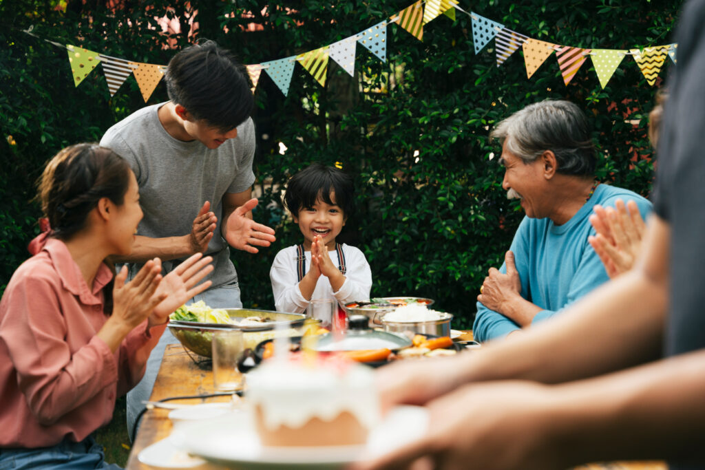 Family celebrates birthday party with cake outdoors